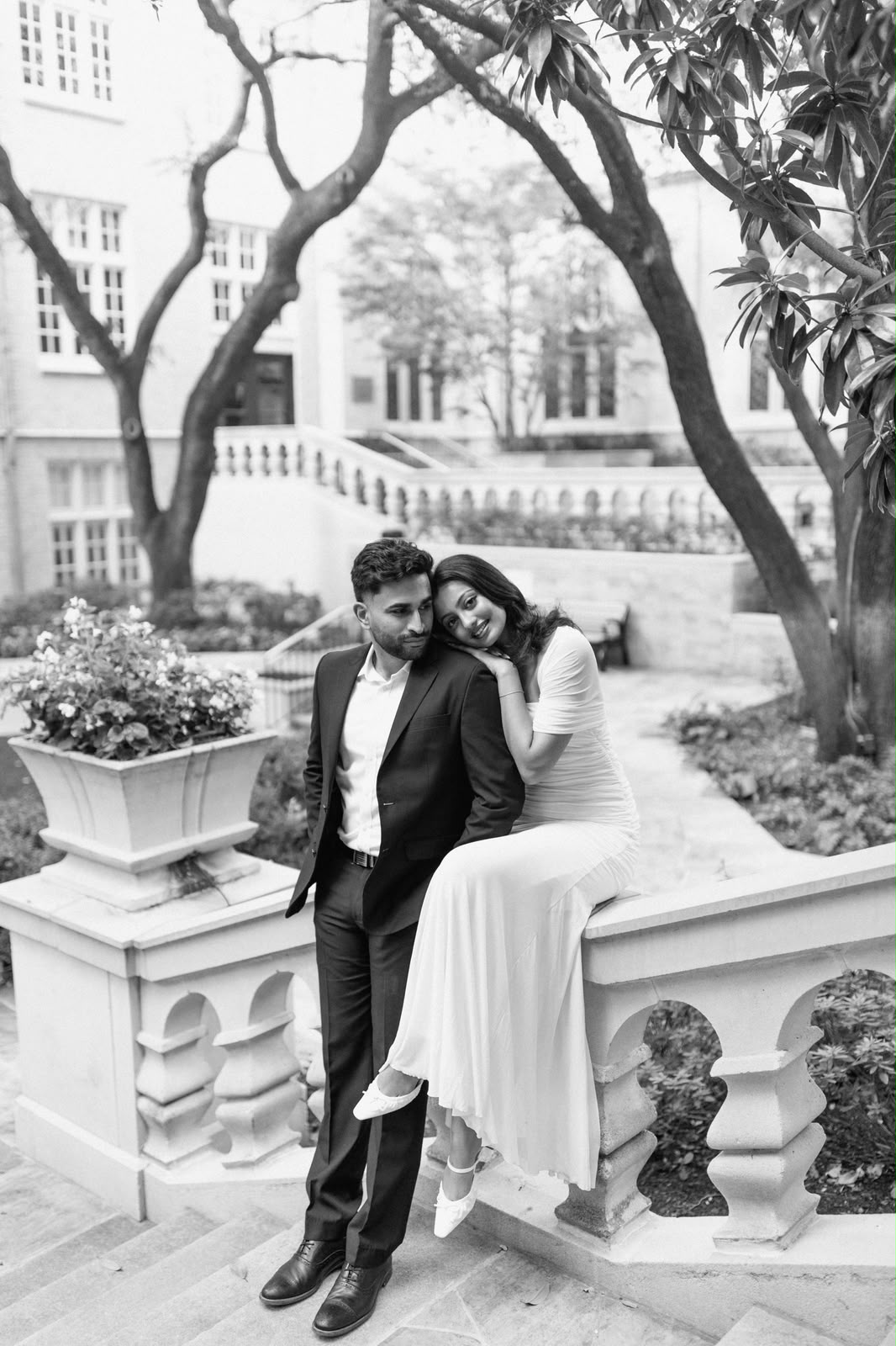Angela leans on Ben beside a garden balcony