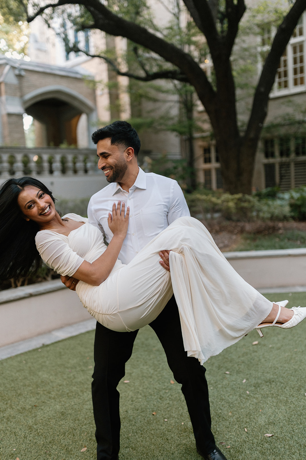 Ben carries Angela as they laugh together in the garden