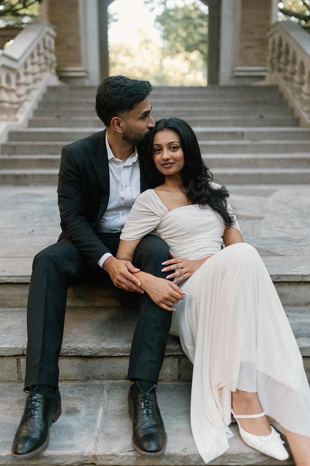 Ben kisses Angela's forehead as they sit together on the steps